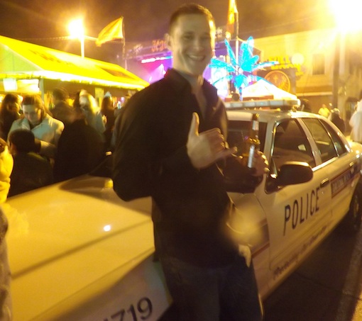 Young man boldly holds up beer nearcop car during New Years on Main Street in Daytona / Headline Surfer®