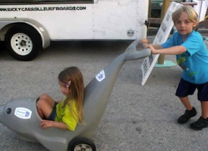Boy pushes his kid sister in a dolphin mobile during Seaside Fiesta in NSB.