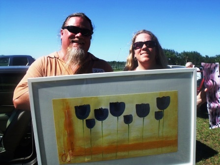 Tod and Amanda Chismark display this painting from the arts fundraiser in NSB 